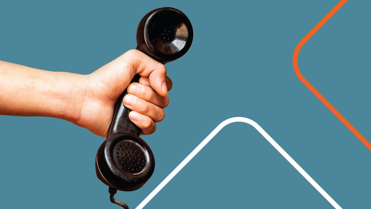 Hand holding an analog landline telephone receiver.